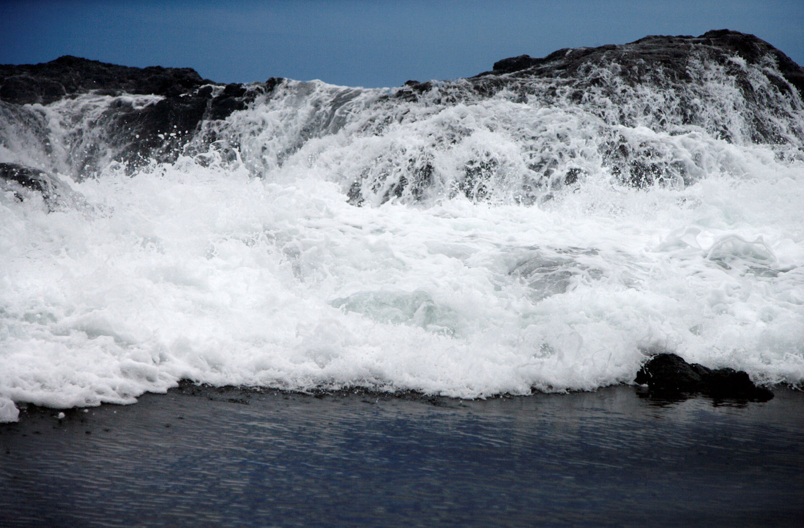 a photo of a huge wave breaking on a rock