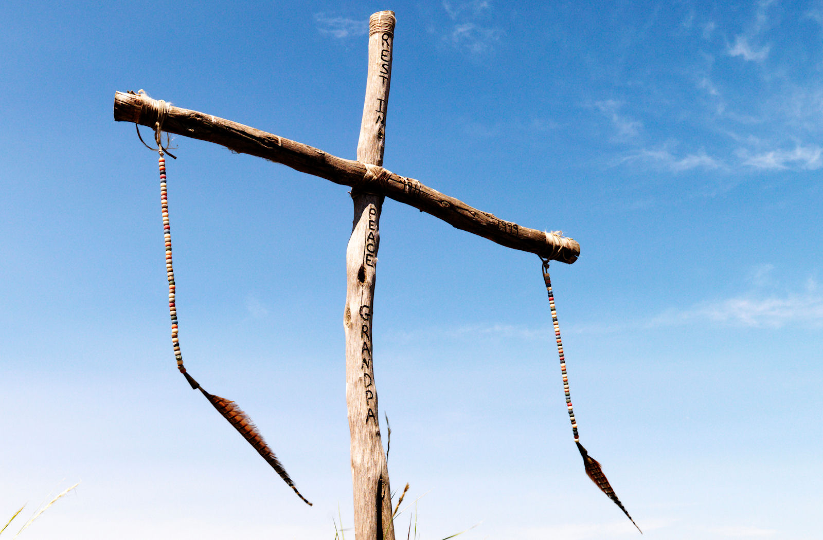 a photo of a rough wooden cross against a blue sky